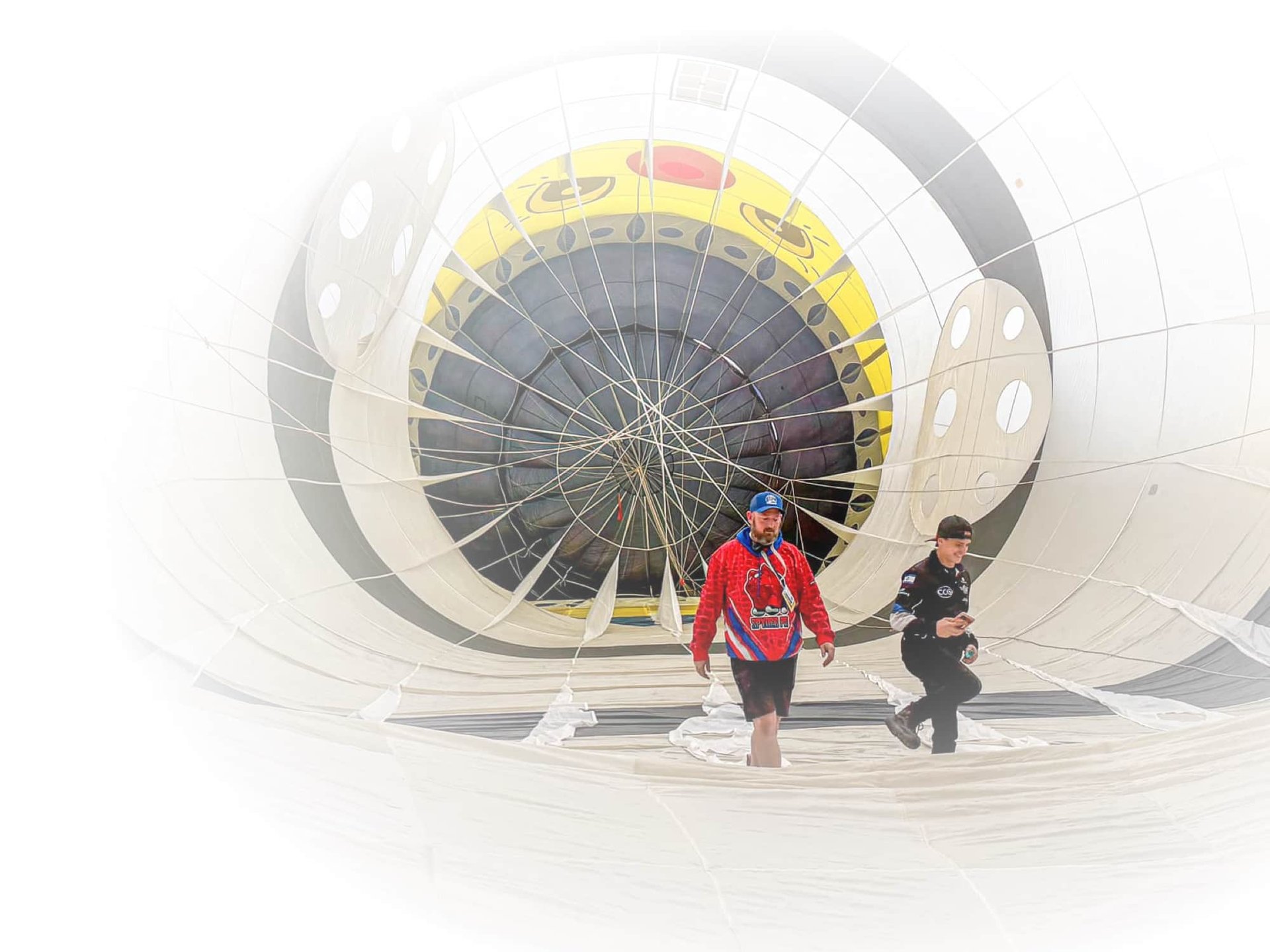 Two people standing inside a large hot air balloon envelope, preparing for flight